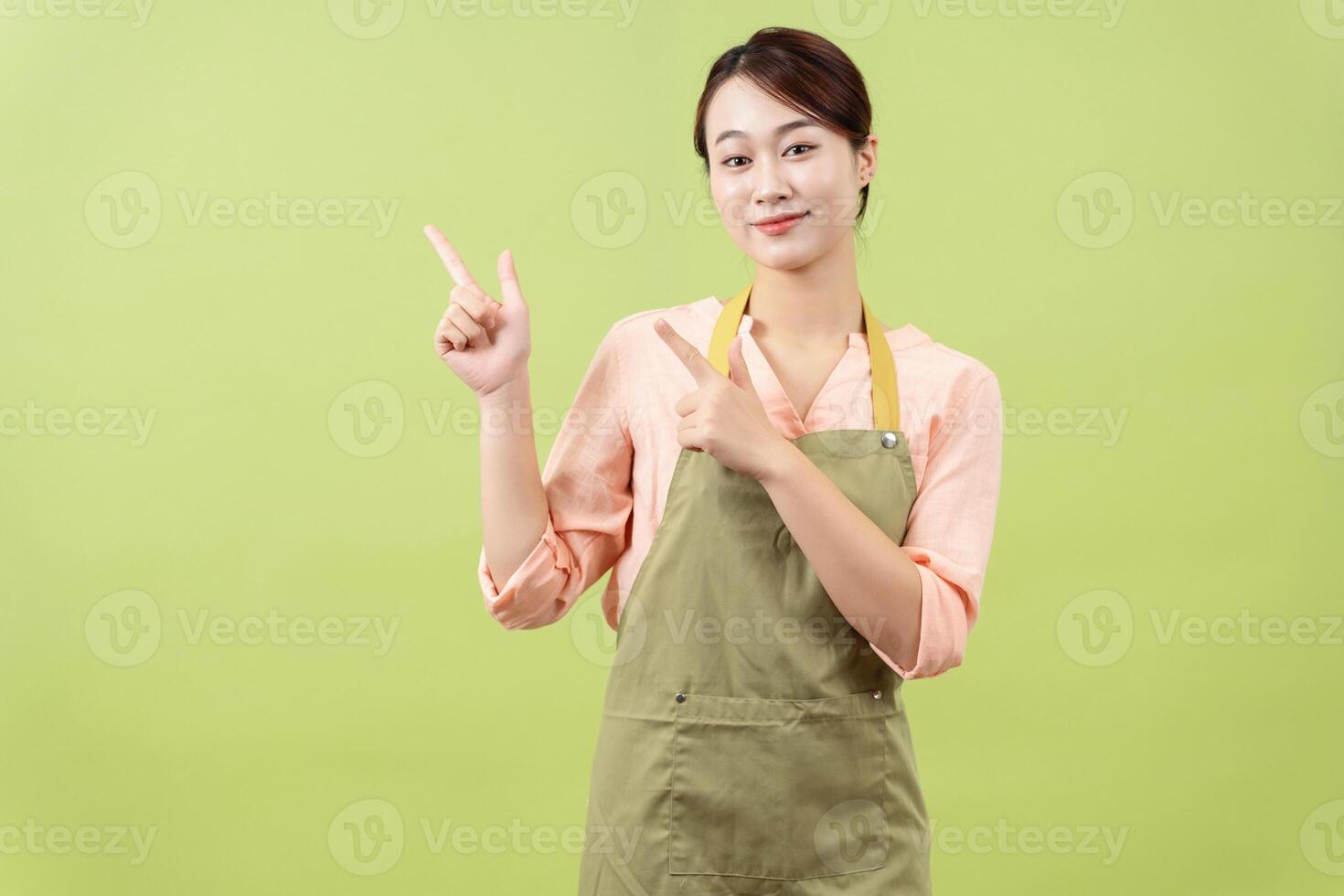 Photo of young Asian female housekeeper on green background