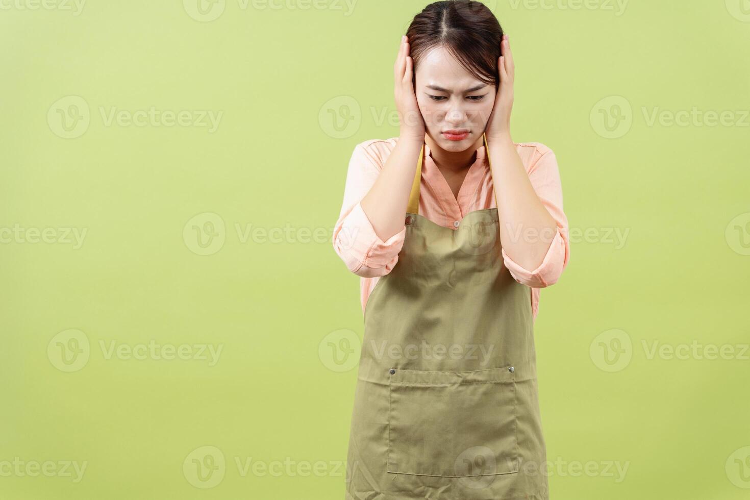 Photo of young Asian female housekeeper on green background
