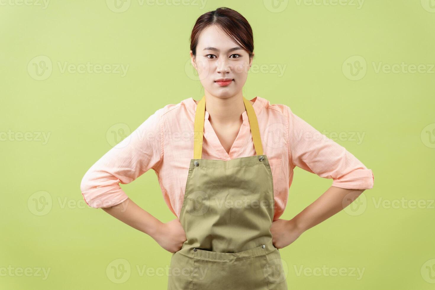 Photo of young Asian female housekeeper on green background