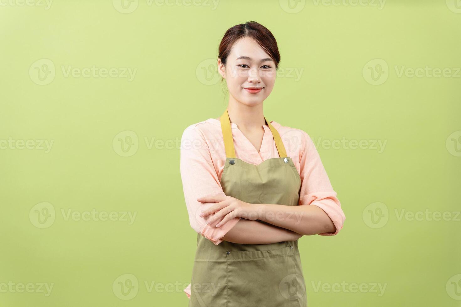 Photo of young Asian female housekeeper on green background