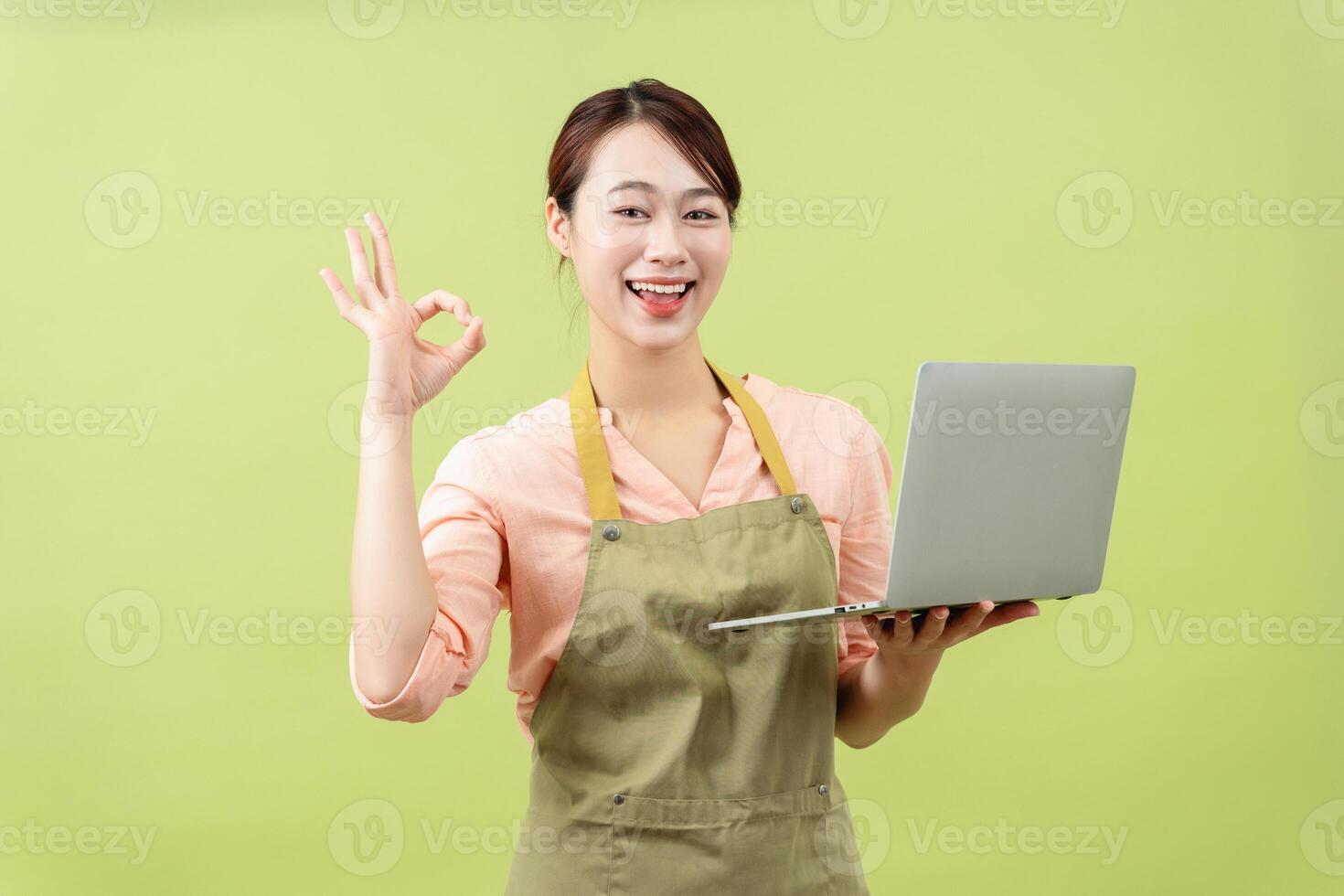 Photo of young Asian female housekeeper on green background