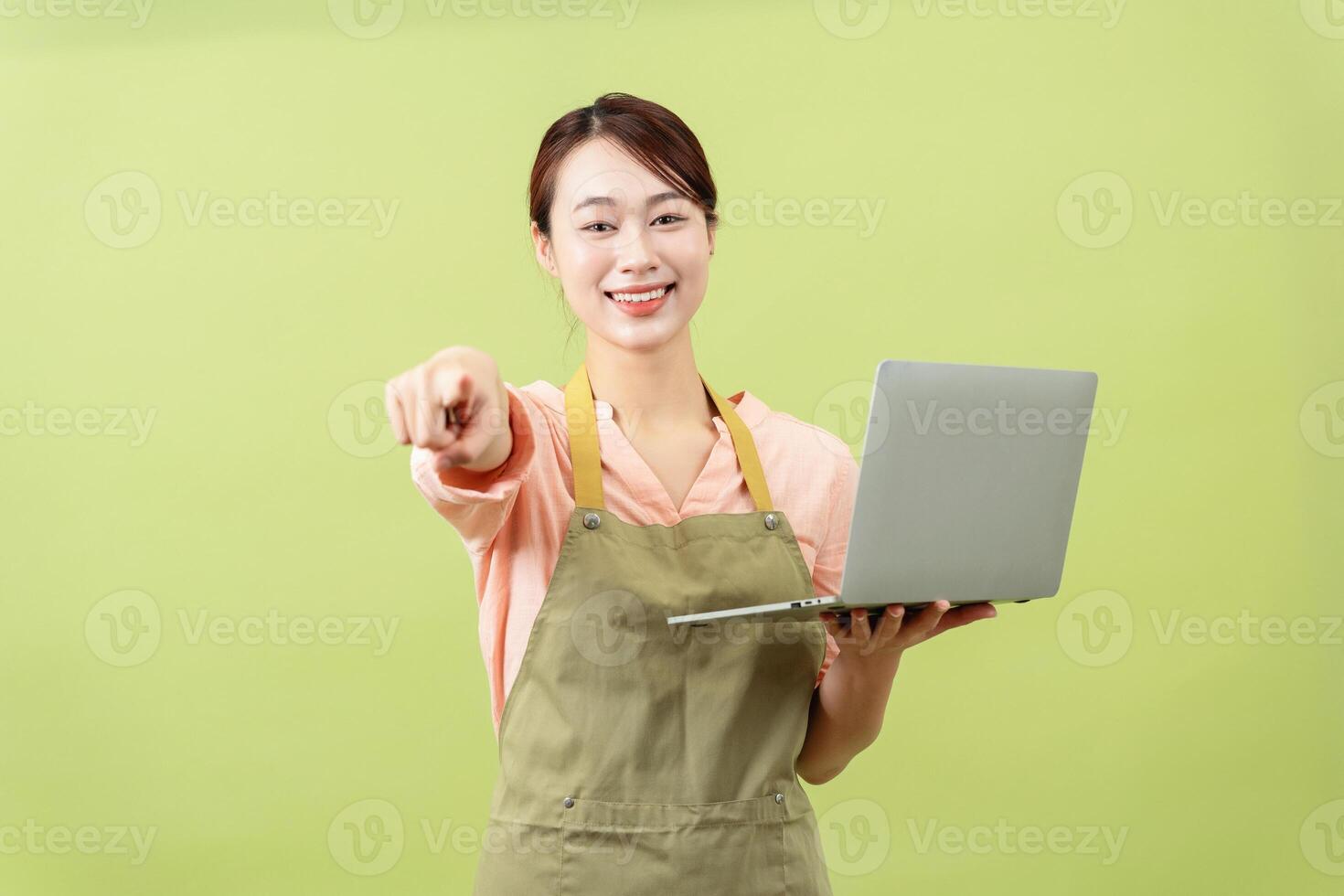 Photo of young Asian female housekeeper on green background