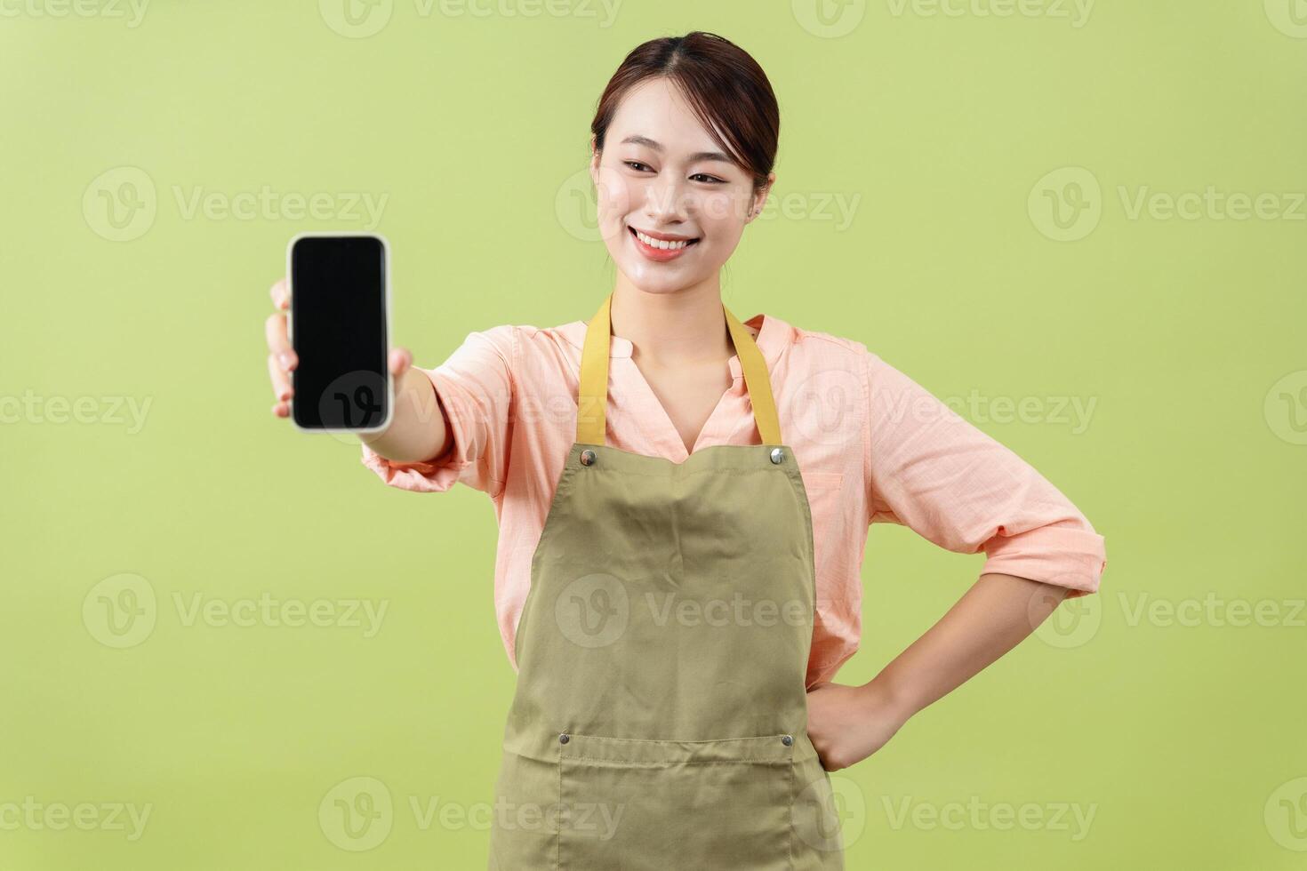 Photo of young Asian female housekeeper on green background