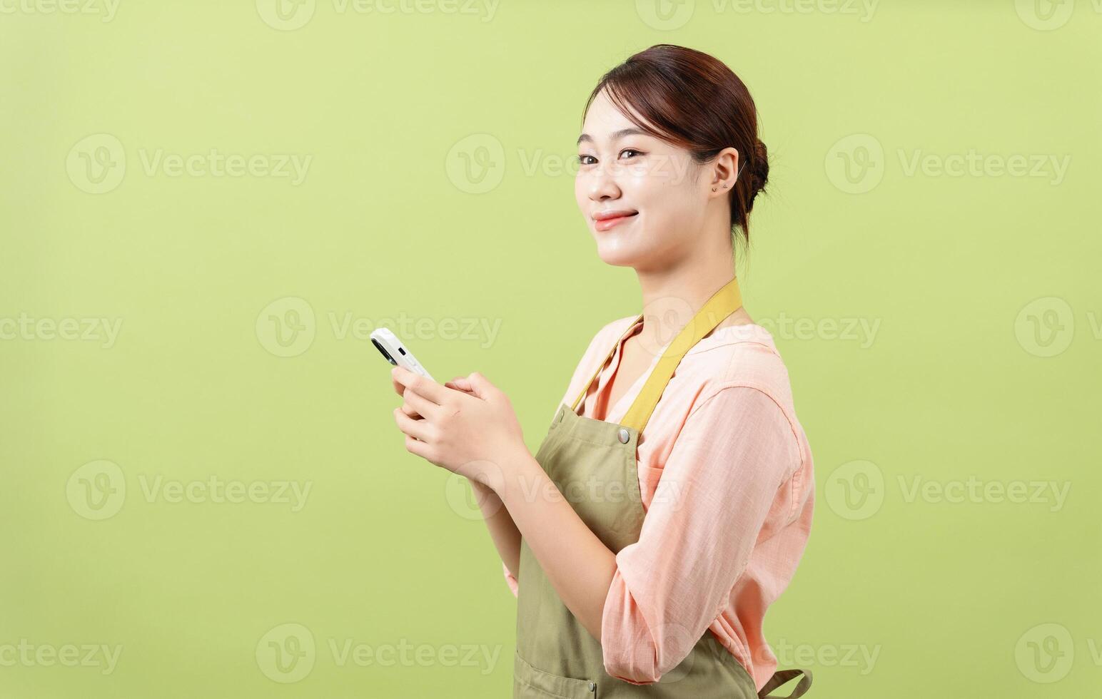 Photo of young Asian female housekeeper on green background