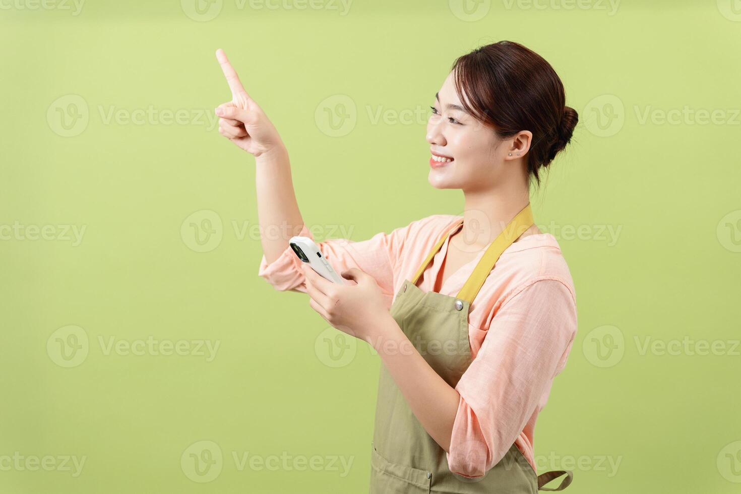 Photo of young Asian female housekeeper on green background