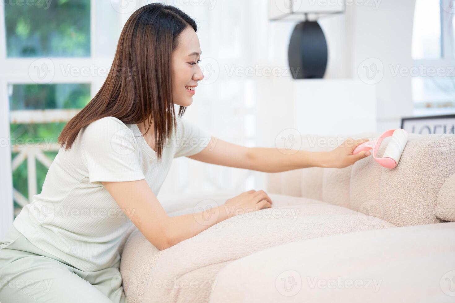 joven asiático mujer limpieza sofá foto