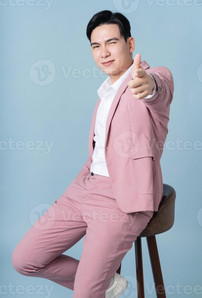 Photo of young Asian businessman wearing pink suit on background