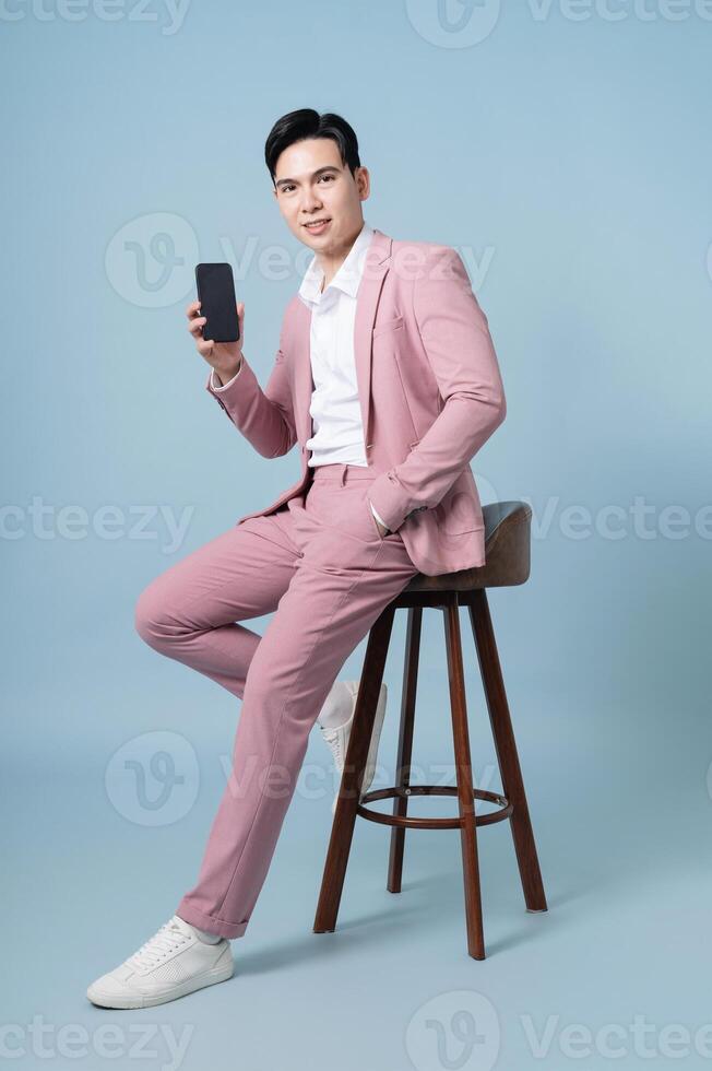 Photo of young Asian businessman wearing pink suit on background