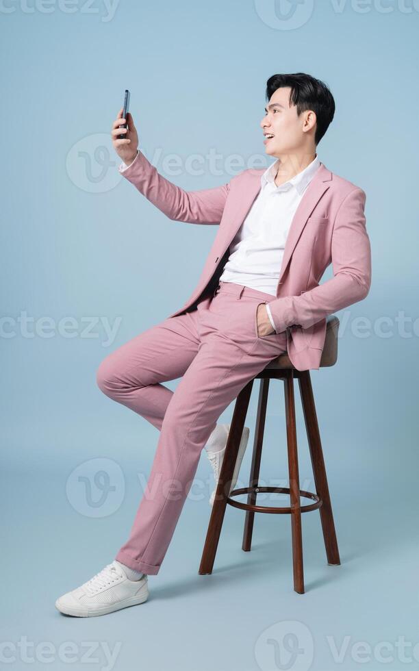 Photo of young Asian businessman wearing pink suit on background