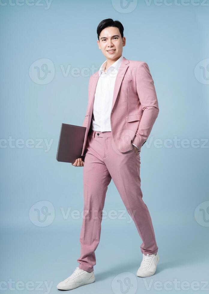 Photo of young Asian businessman wearing pink suit on background