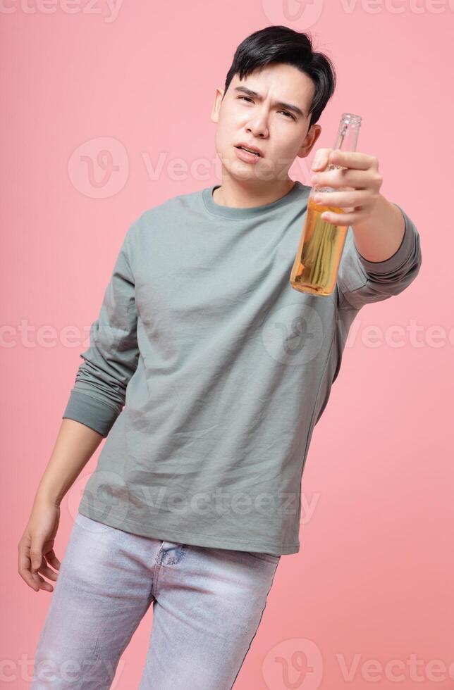 Photo of young Asian man drinking alcohol on background