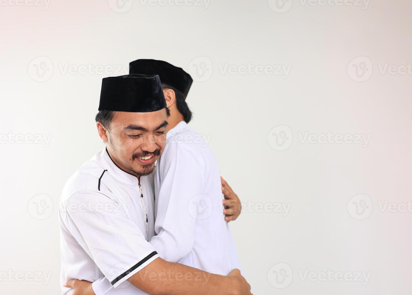 Two Young Indonesian Muslim Male Hug and Smiling during Eid Al Fitr Festive photo