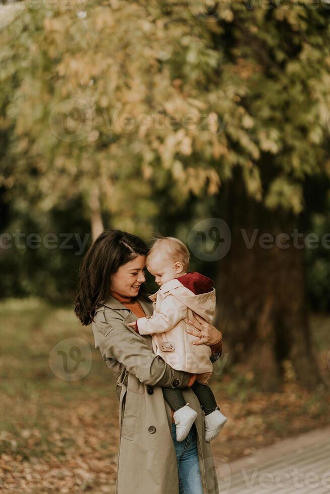 joven mujer participación linda bebé niña en el otoño parque foto