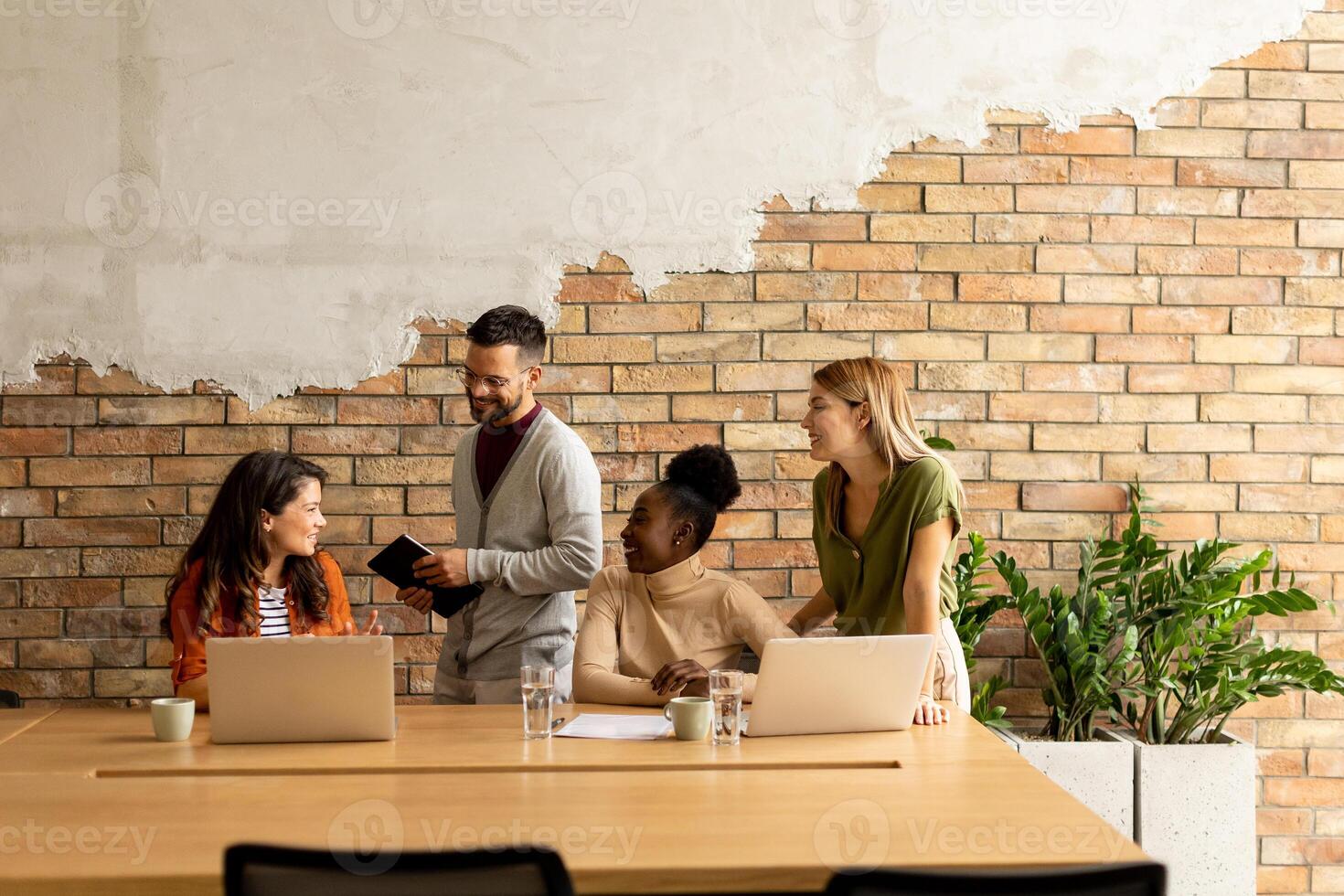 Young multiethnic startup team working by the brick wall in the industrial style office photo