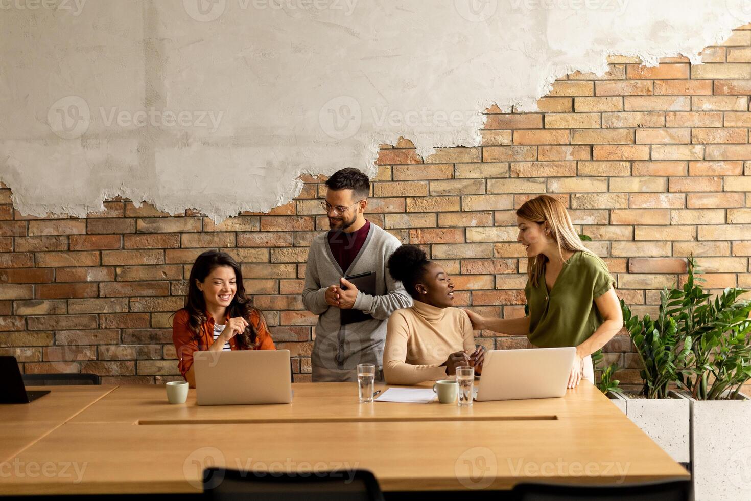 Young multiethnic startup team working by the brick wall in the industrial style office photo