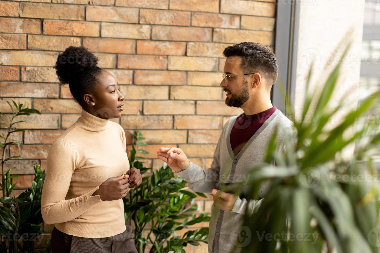 Young multiethnic business couple with digital tablet standing and discussing in the modern office photo