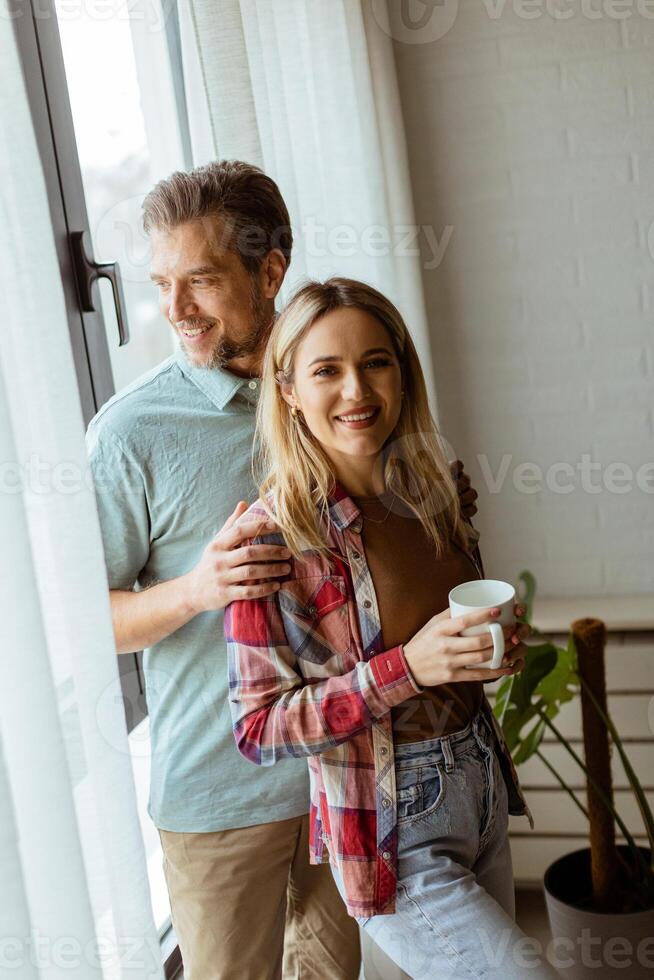 oferta abrazo por el ventana, Pareja compartiendo un sereno momento adentro foto