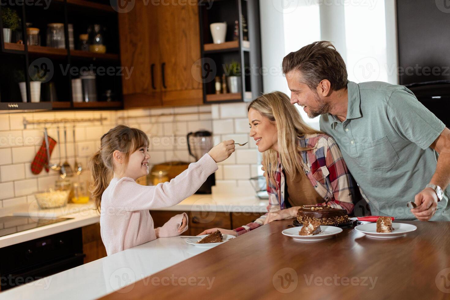 Joyful Family Enjoying Homemade Chocolate Cake in Cozy Kitchen photo