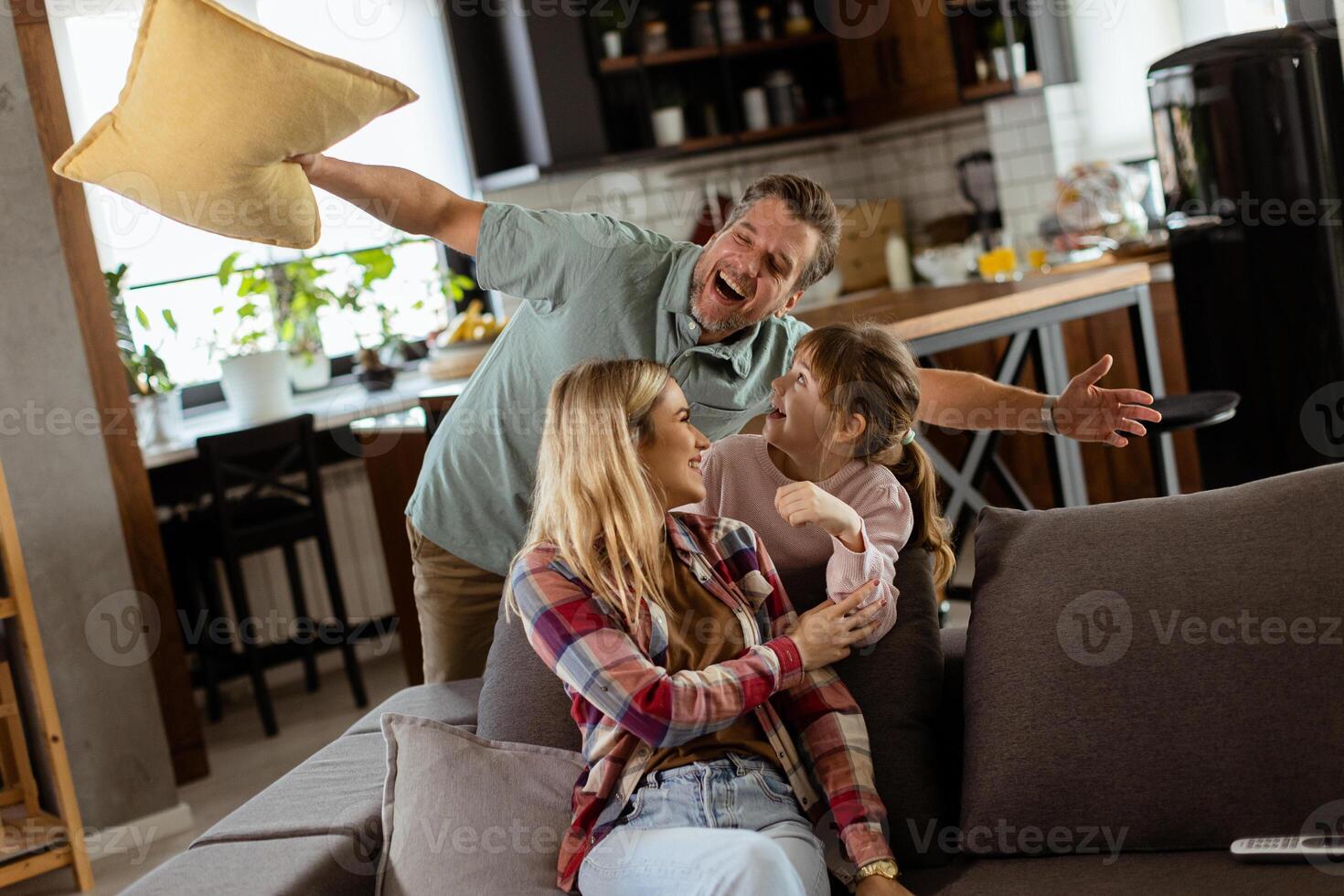 Playful family pillow fight in a cozy living room at dusk photo