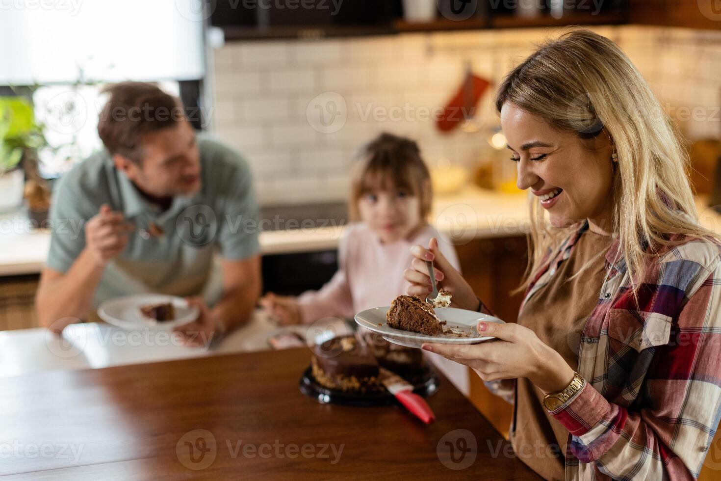 Joyful Family Enjoying Homemade Chocolate Cake in Cozy Kitchen photo