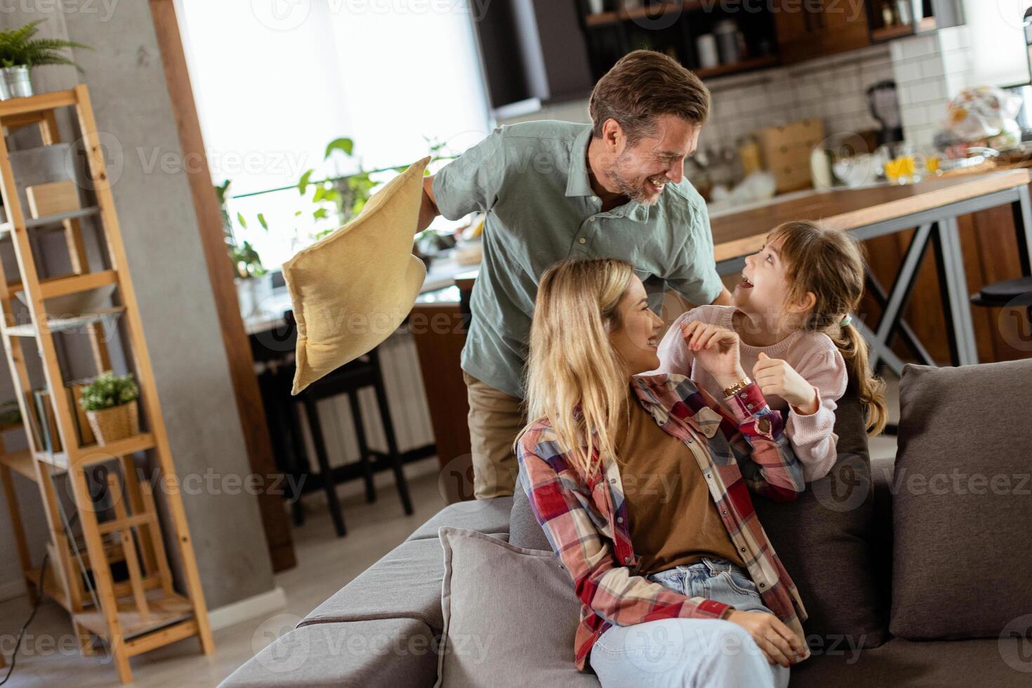 Playful family pillow fight in a cozy living room at dusk photo