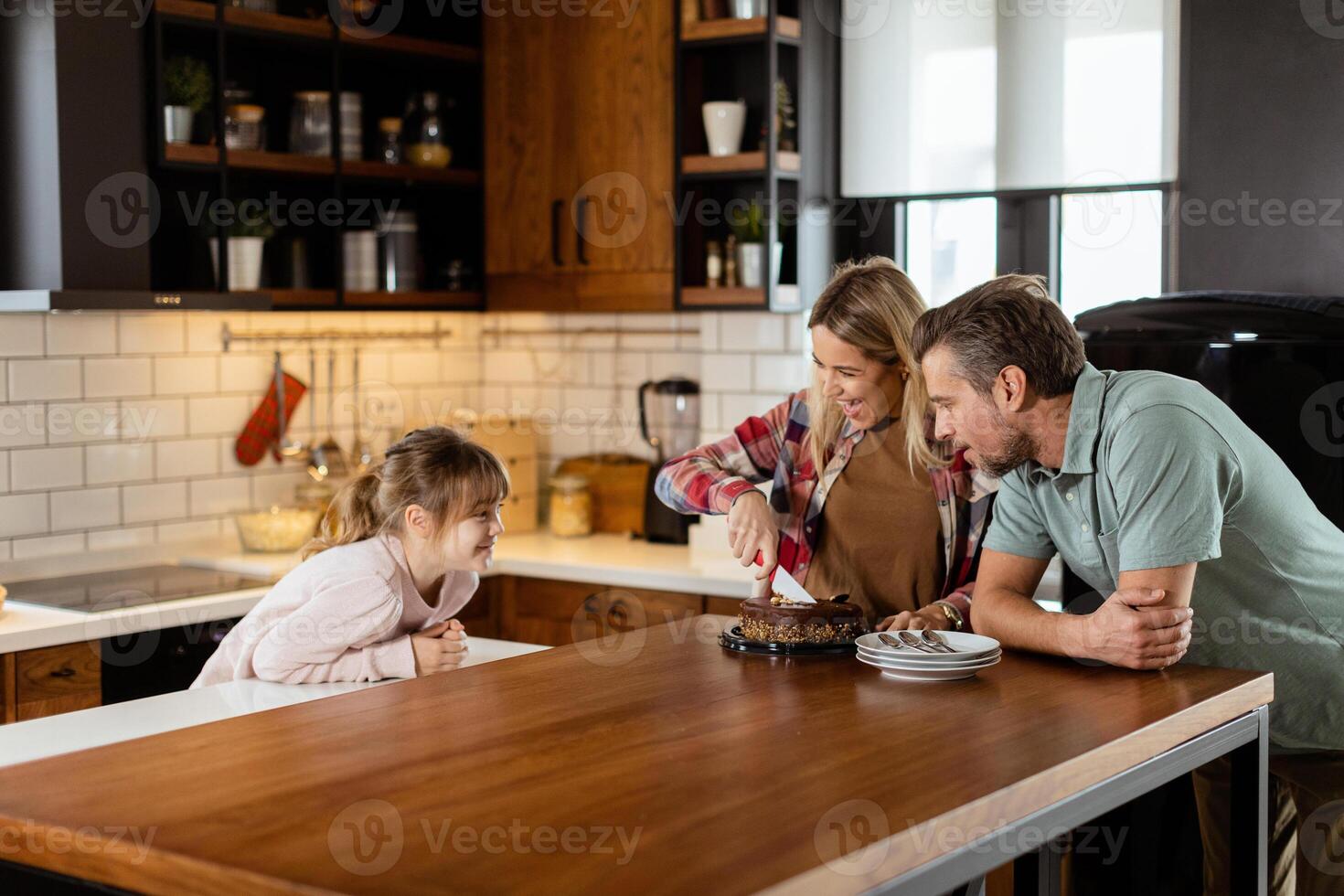 Joyful Family Enjoying Homemade Chocolate Cake in Cozy Kitchen photo