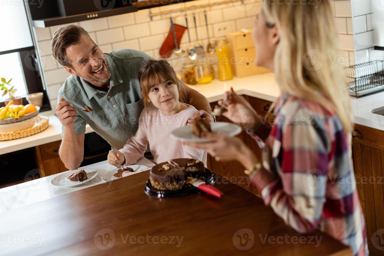 Joyful Family Enjoying Homemade Chocolate Cake in Cozy Kitchen photo