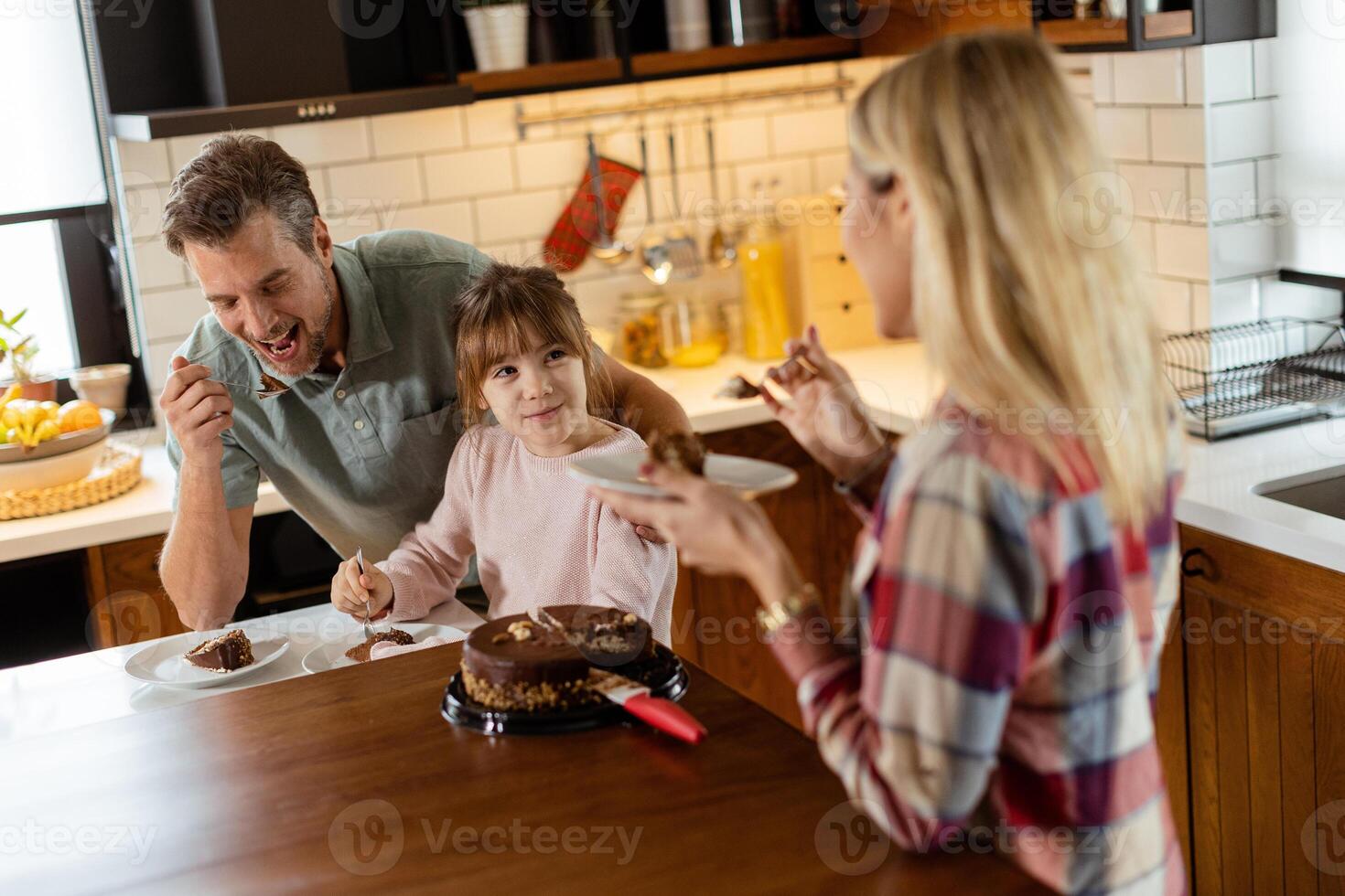 Joyful Family Enjoying Homemade Chocolate Cake in Cozy Kitchen photo