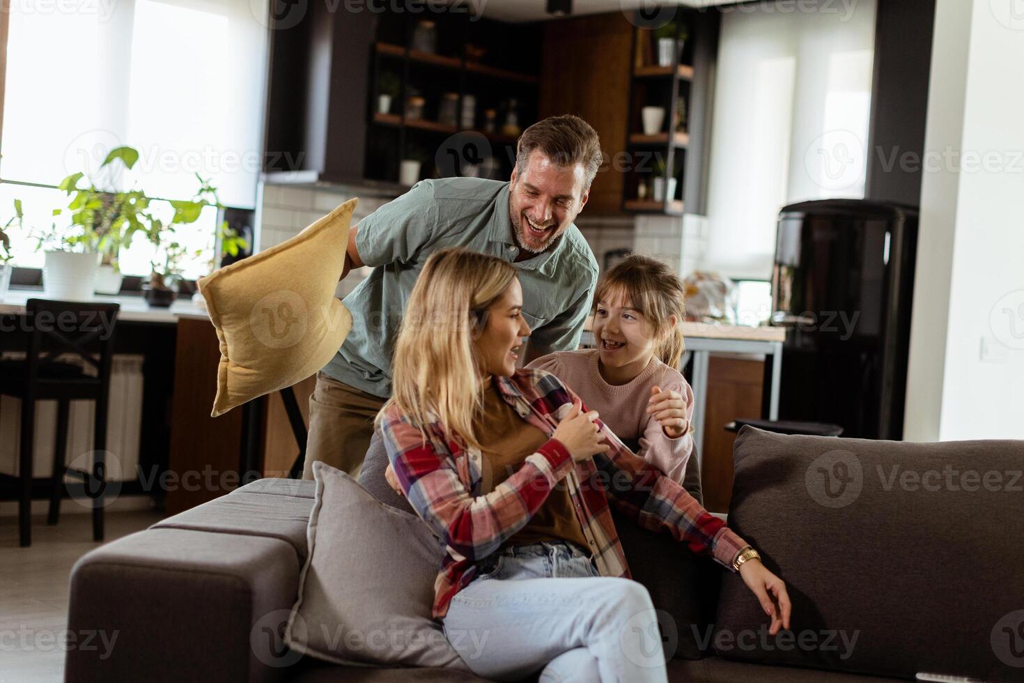 Playful family pillow fight in a cozy living room at dusk photo