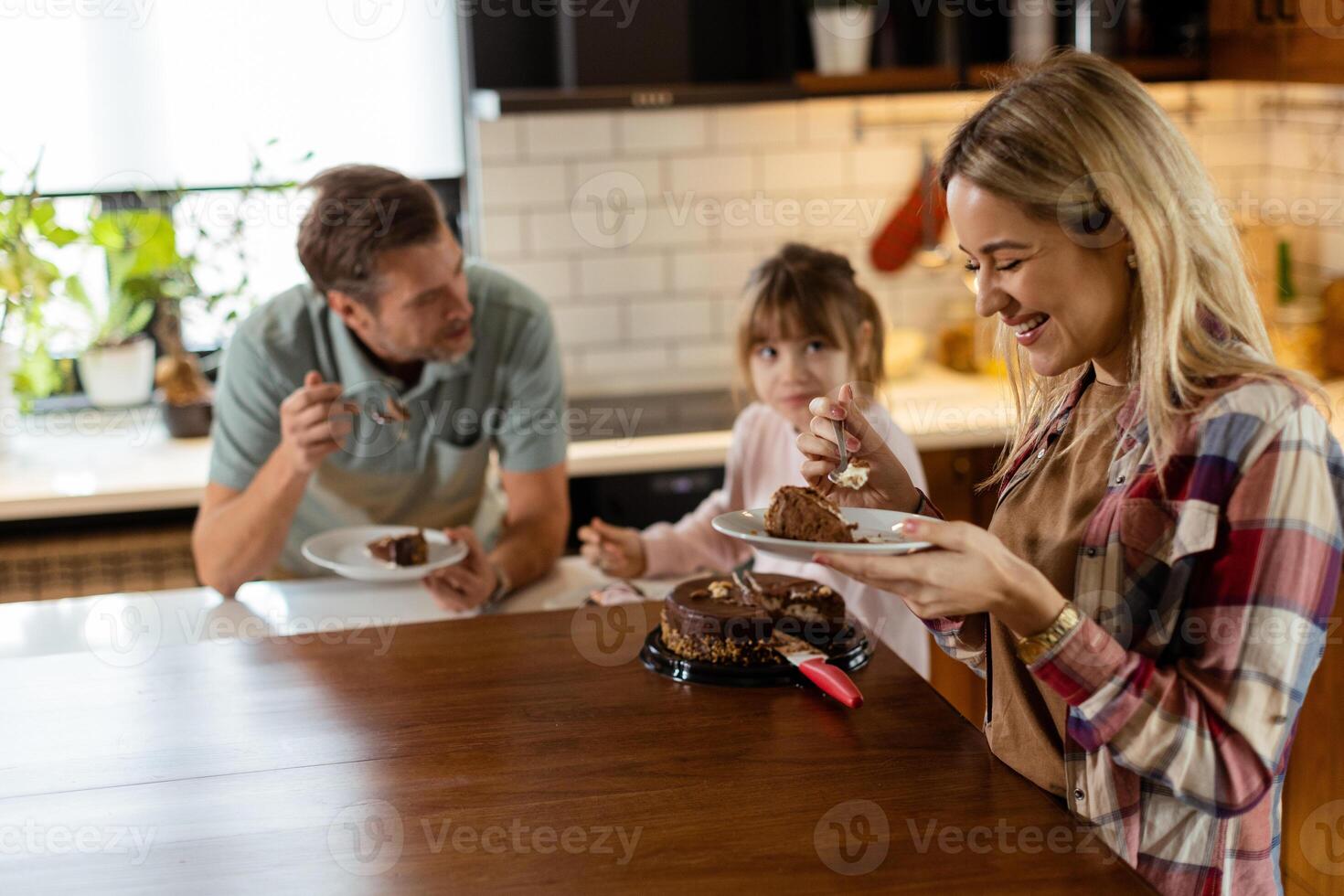Joyful Family Enjoying Homemade Chocolate Cake in Cozy Kitchen photo