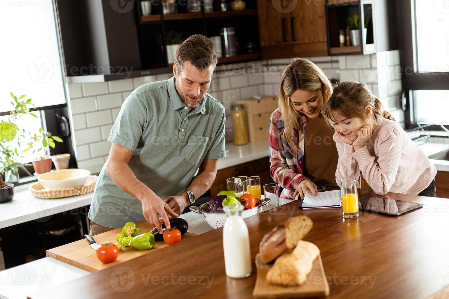 Family chatting and preparing food around a bustling kitchen counter filled with fresh ingredients and cooking utensils photo