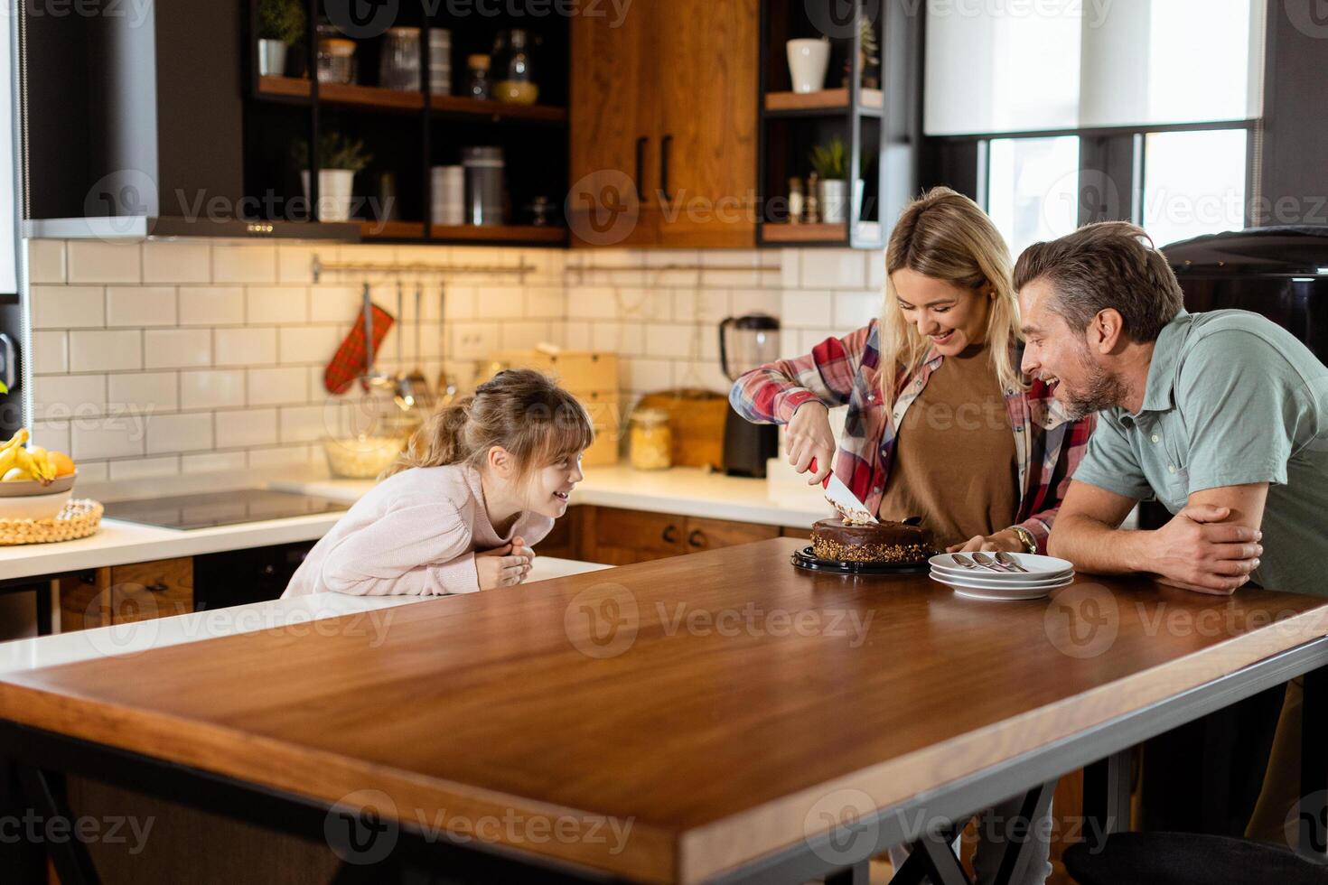 Joyful Family Enjoying Homemade Chocolate Cake in Cozy Kitchen photo