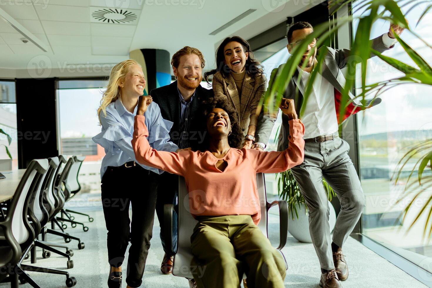Joyful Office Colleagues Engage in a Playful Chair Race on a Sunny Afternoon. photo