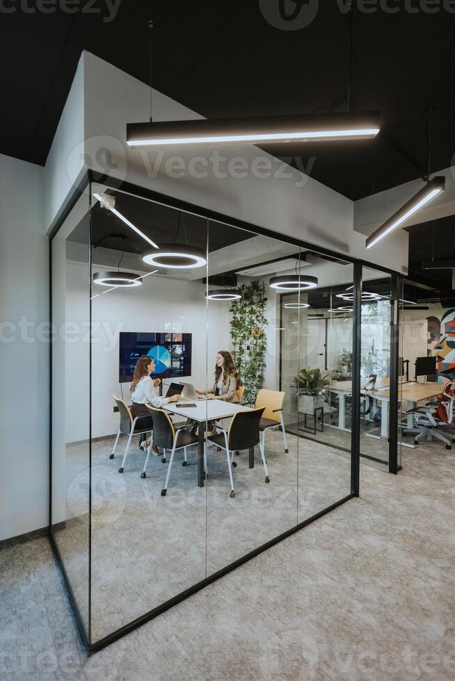 Young business women discussing in cubicle at the office photo