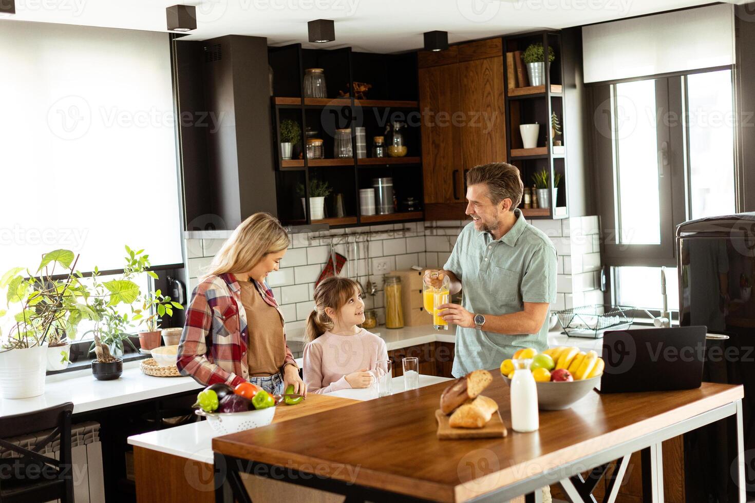 Family chatting and preparing food around a bustling kitchen counter filled with fresh ingredients and cooking utensils photo