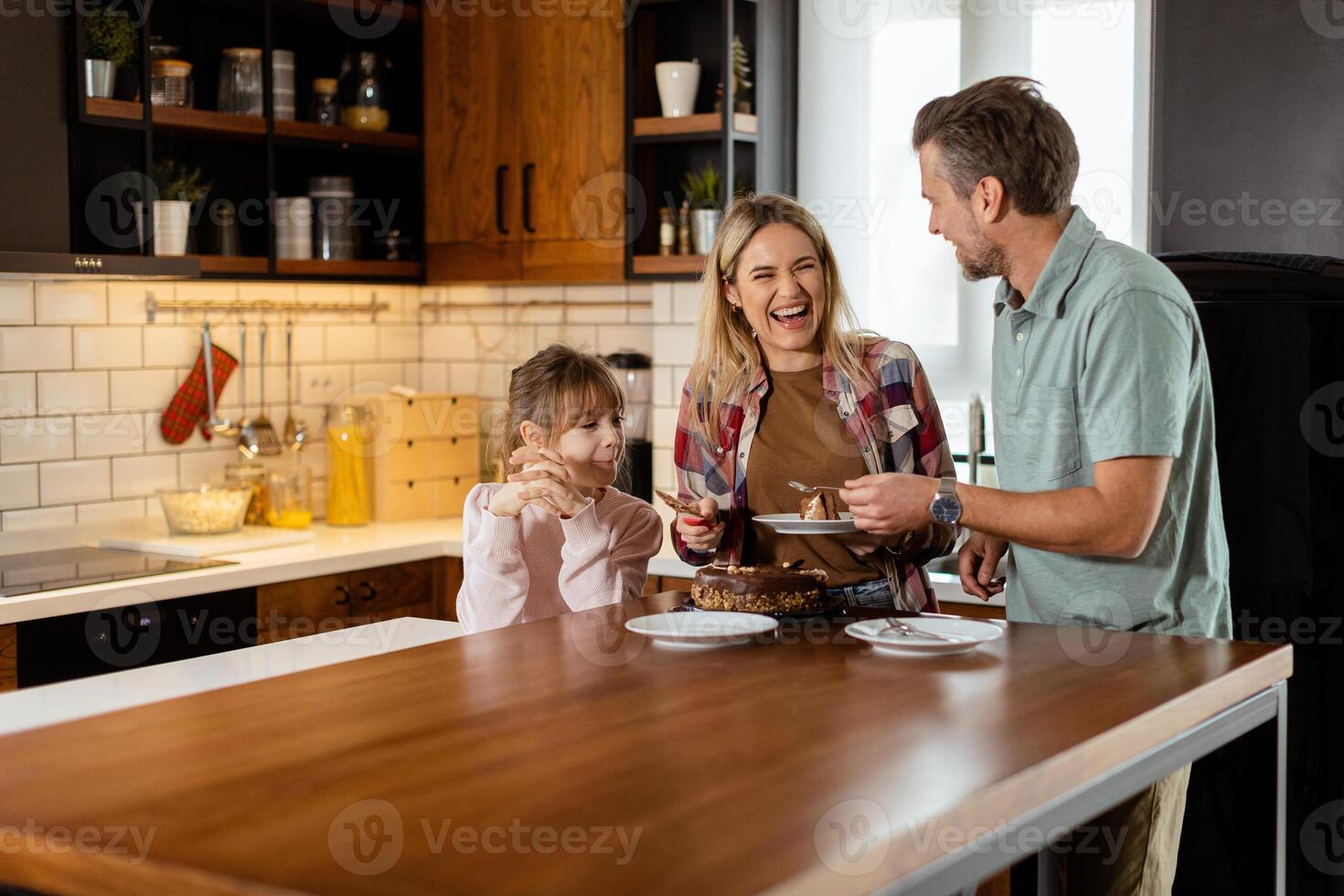 Joyful Family Enjoying Homemade Chocolate Cake in Cozy Kitchen photo