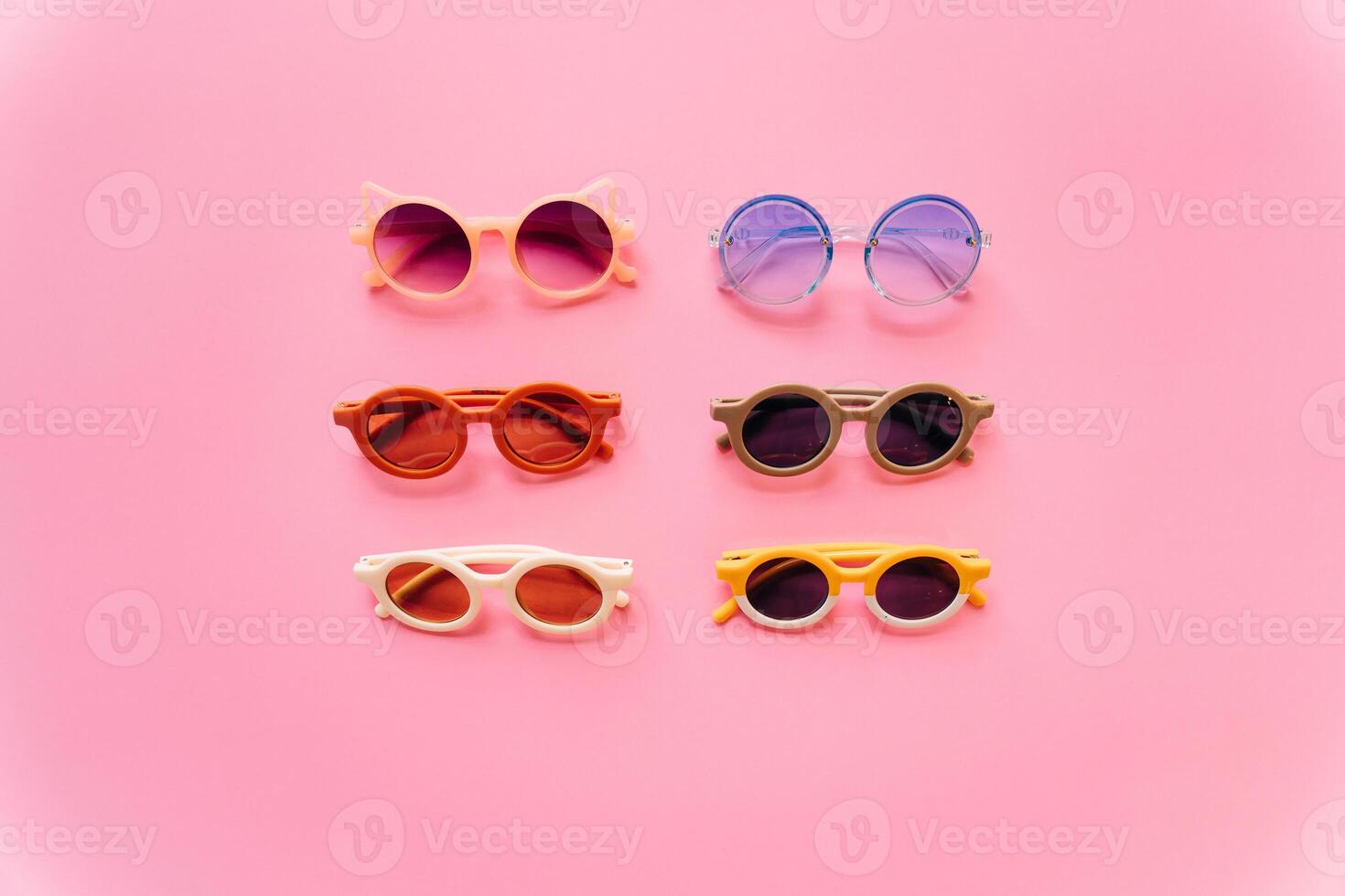 Different stylish sunglasses on pink background photo