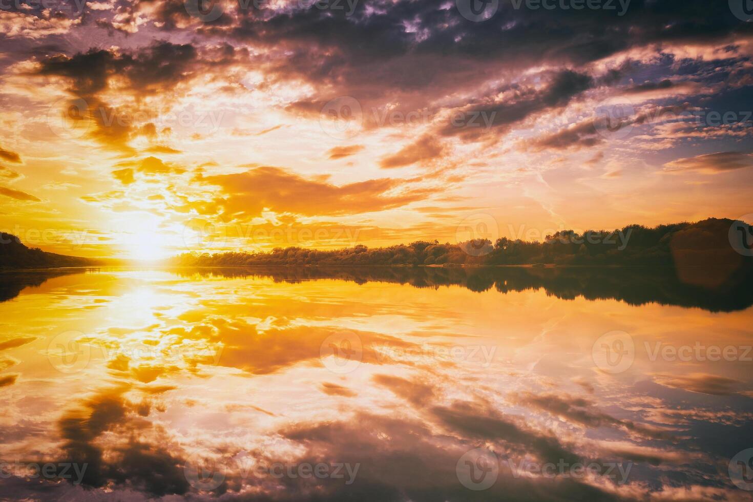 Sunrise or sunset on a lake or river with cloudy sky reflection in the water in summertime. Aesthetics of vintage film. photo