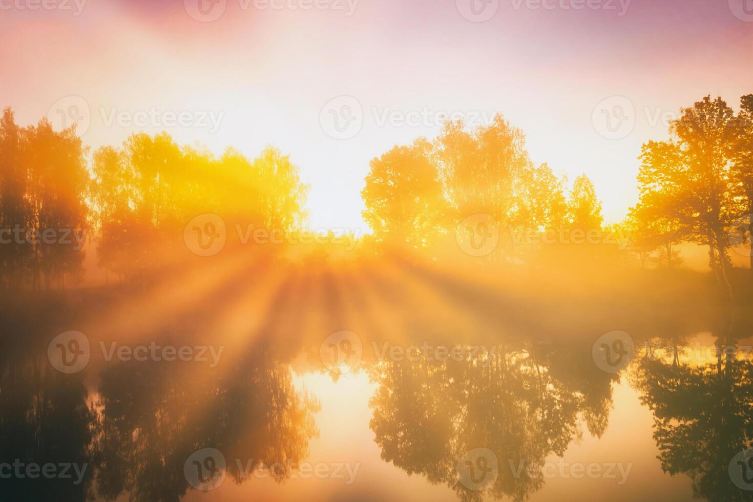 Dawn on a lake or river with a sky reflected in the water, birch trees on the shore and the sunbeams breaking through them and fog in autumn. Aesthetics of vintage film. photo