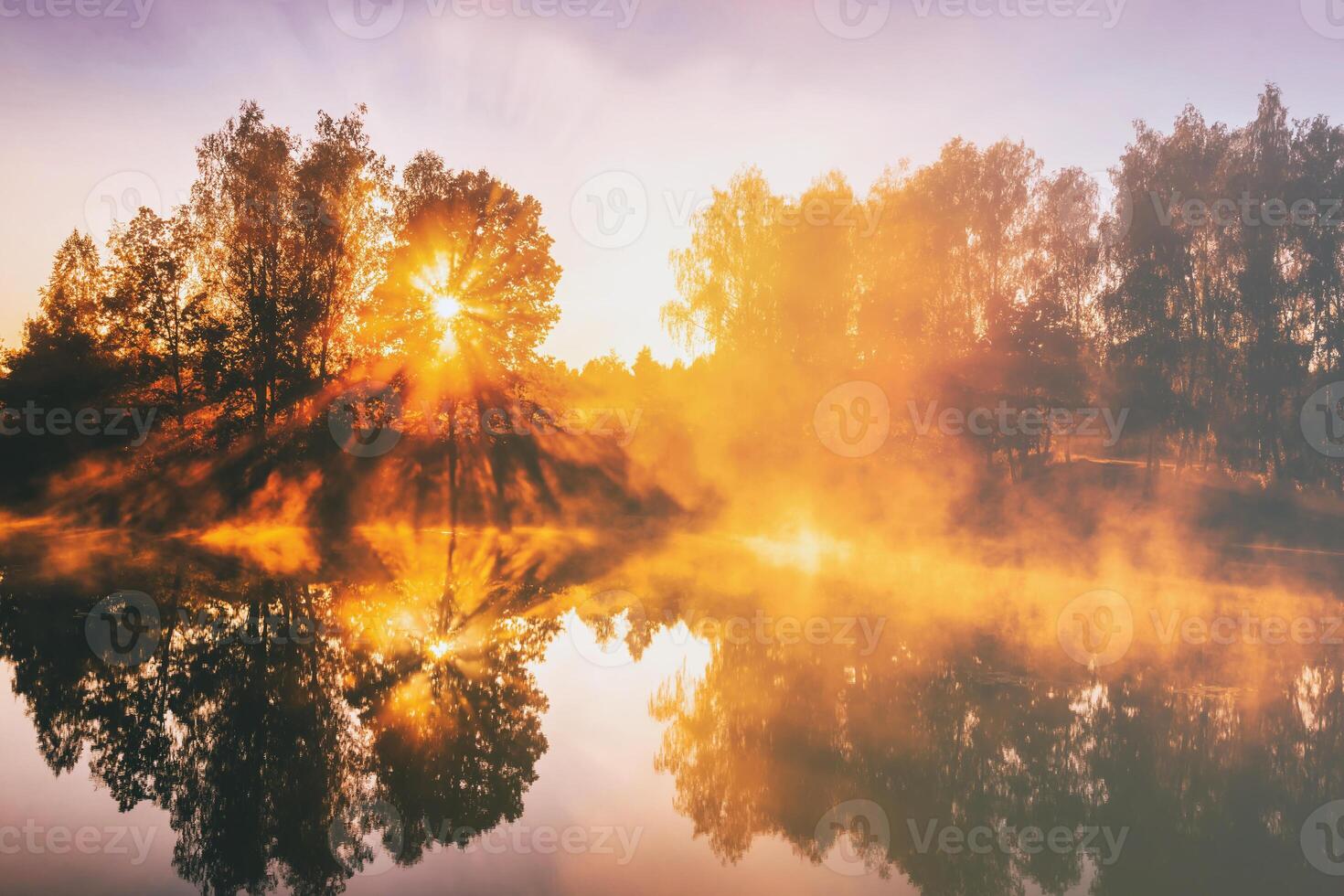 Dawn on a lake or river with a sky reflected in the water, birch trees on the shore and the sunbeams breaking through them and fog in autumn. Aesthetics of vintage film. photo