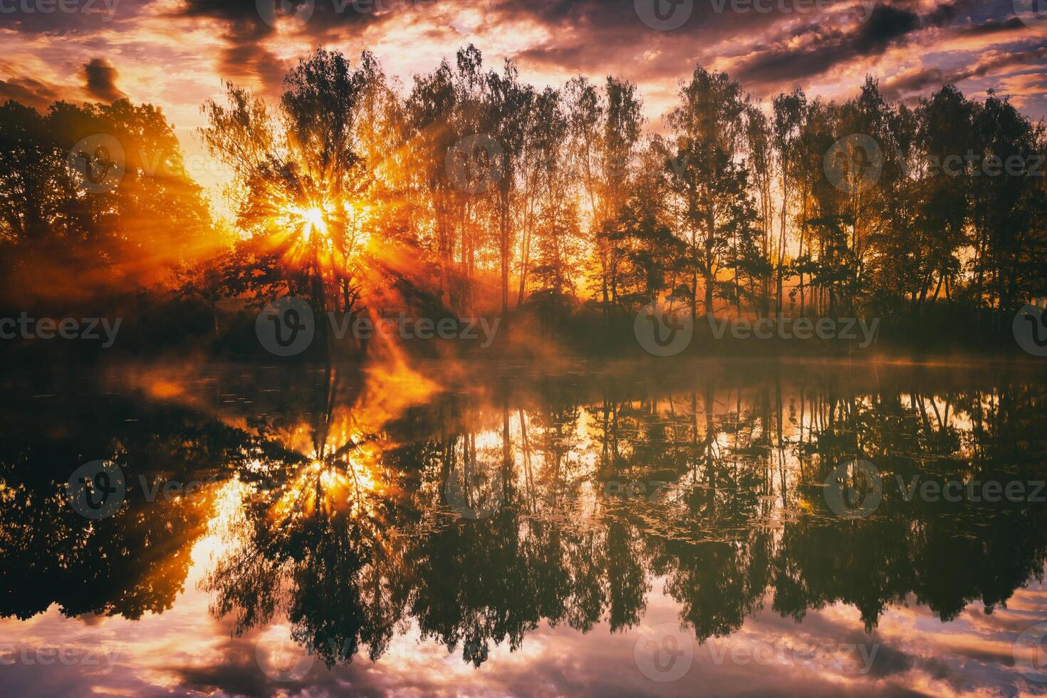 Dawn on a lake or river with a sky reflected in the water, birch trees on the shore and the sunbeams breaking through them and fog in autumn. Aesthetics of vintage film. photo