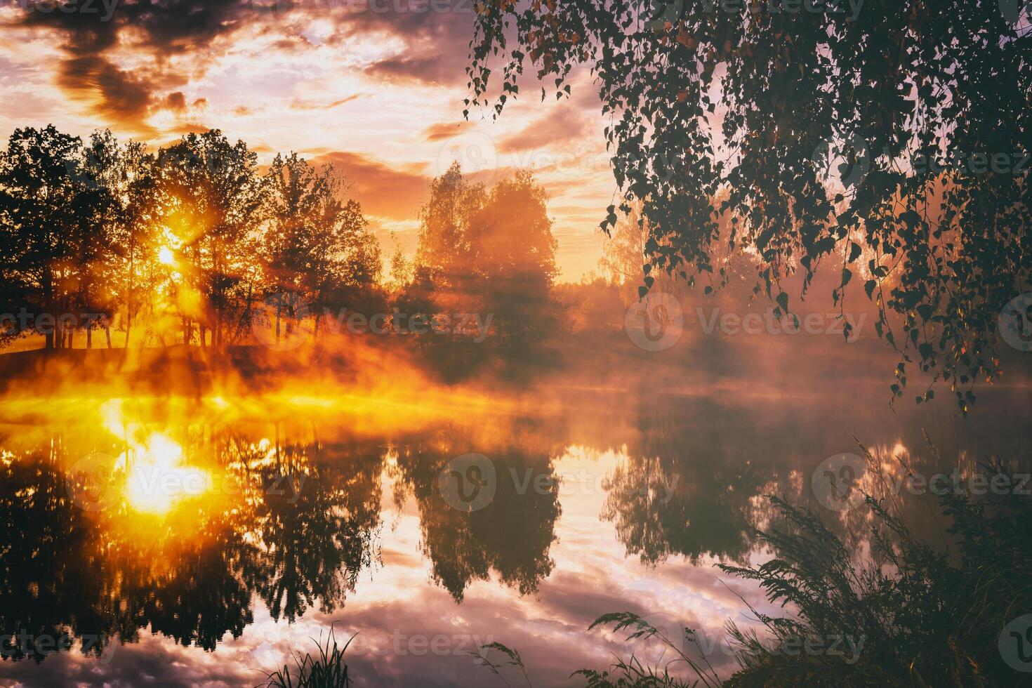 amanecer en un lago o río con un cielo reflejado en el agua, abedul arboles en el apuntalar y el rayos de sol rotura mediante ellos y niebla en otoño. estética de Clásico película. foto