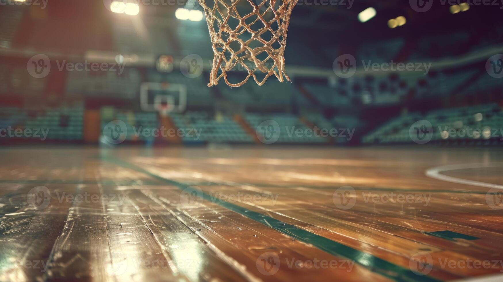 Close-up of a basketball hoop on an empty, well-lit professional court, showcasing the net's intricate details against the soft-focused background of the gleaming wooden floor and the distant seats photo