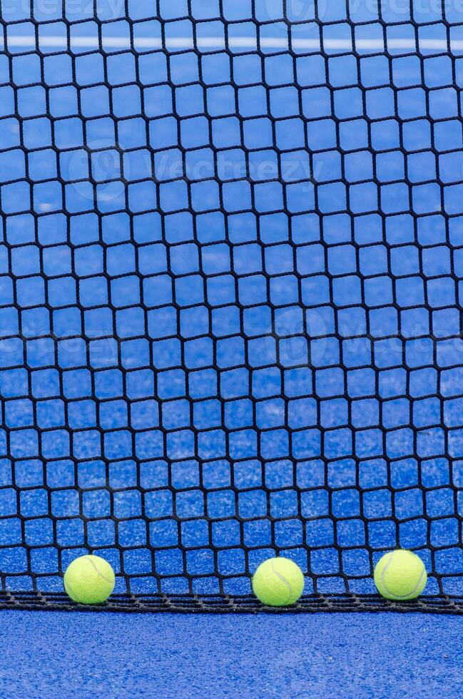 balls next to a paddle tennis court net, racket sports photo