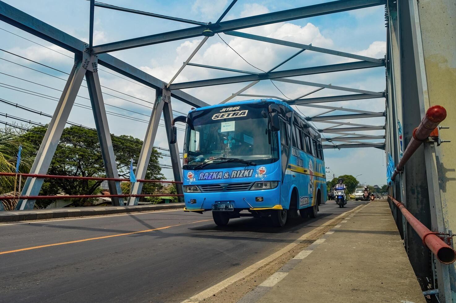 a blue mini bus was passing by on a steel truss bridge, Indonesia, 16 January 2024. photo