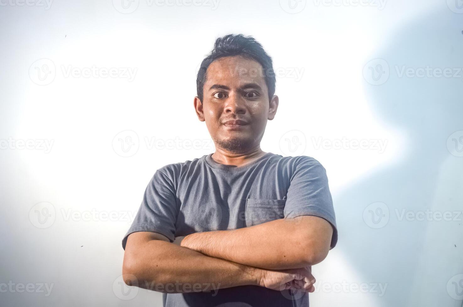 hermoso asiático hombre quien siente orgulloso vistiendo un gris camiseta en un llanura blanco antecedentes foto