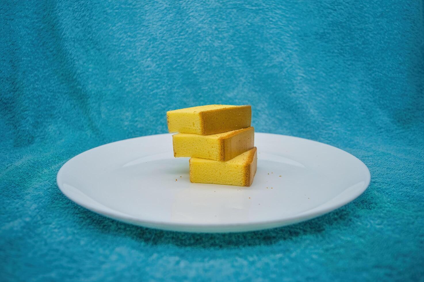 three pieces of cheese cake on a white plate with a turquoise cloth background photo