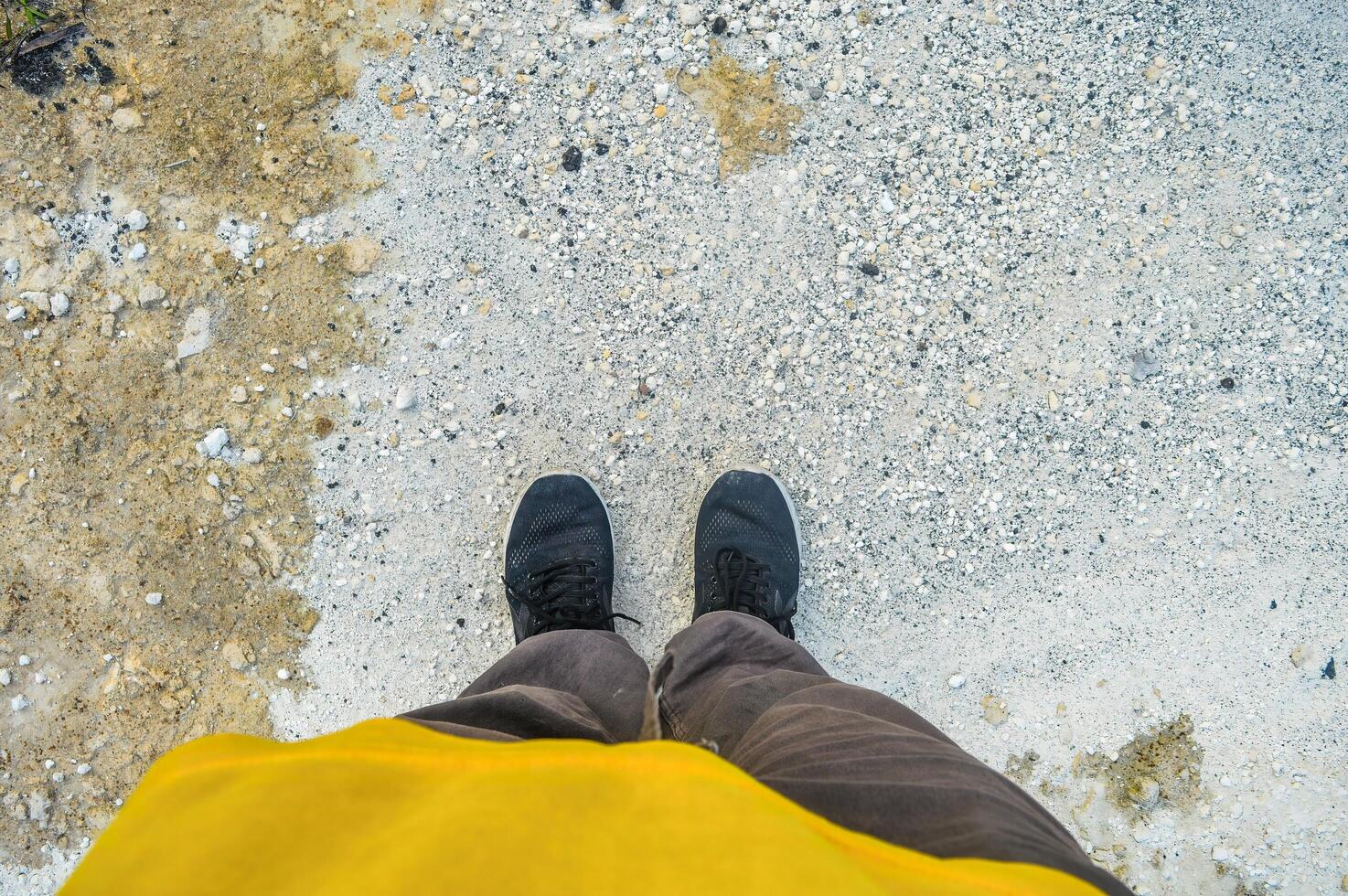 the feet of a person wearing sweatpants standing on white limestone rocks photo