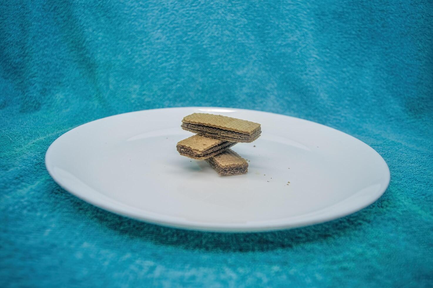 varios obleas o obleas arreglado en un llanura blanco plato en un turquesa antecedentes foto