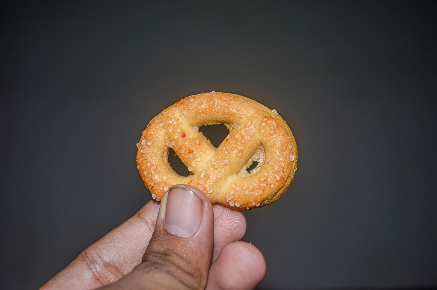 hand holding a biscuit on a dark background photo